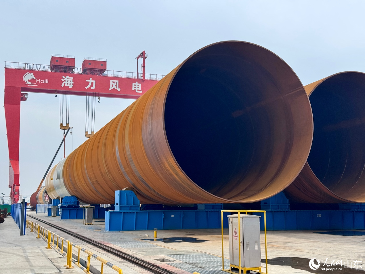 巨型塔筒横卧于场地,等待起吊组装。人民网 郑昕桥摄